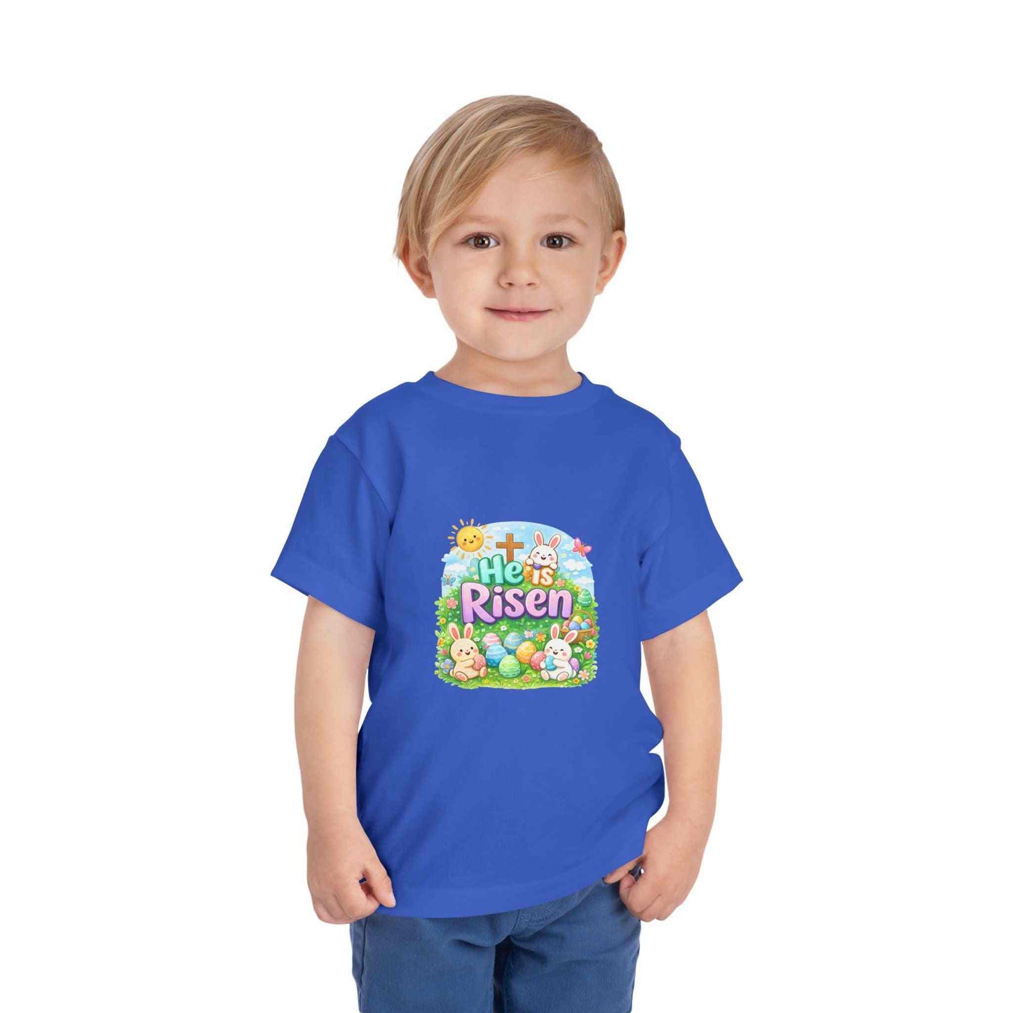 He Is Risen toddler tee with Easter bunny, cross, and eggs illustration on soft pastel fabric