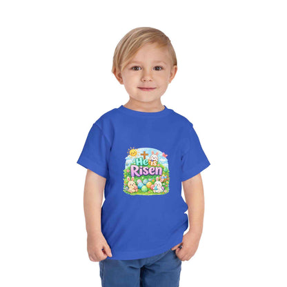 He Is Risen toddler tee with Easter bunny, cross, and eggs illustration on soft pastel fabric