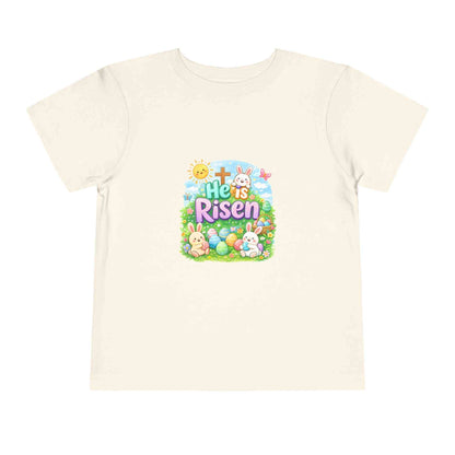 He Is Risen toddler tee with Easter bunny, cross, and pastel eggs design for kids