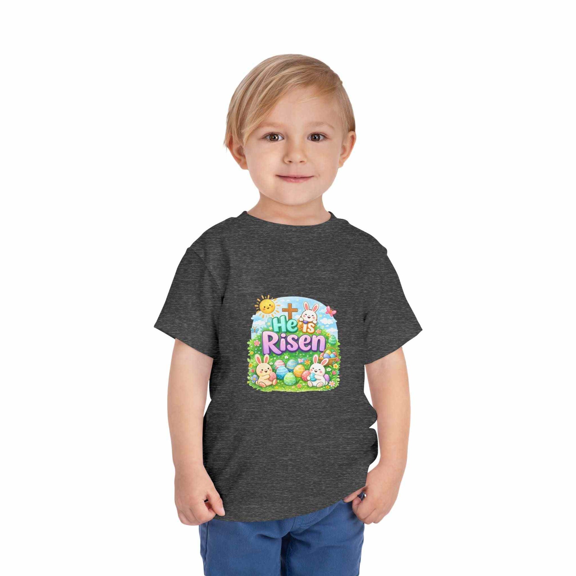 He Is Risen toddler tee with Easter bunny, cross, and pastel eggs design for kids