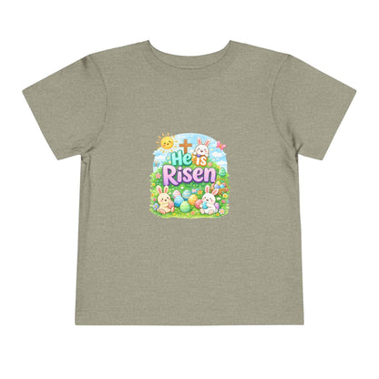 He Is Risen toddler tee with Easter bunny, cross, and pastel eggs design for kids
