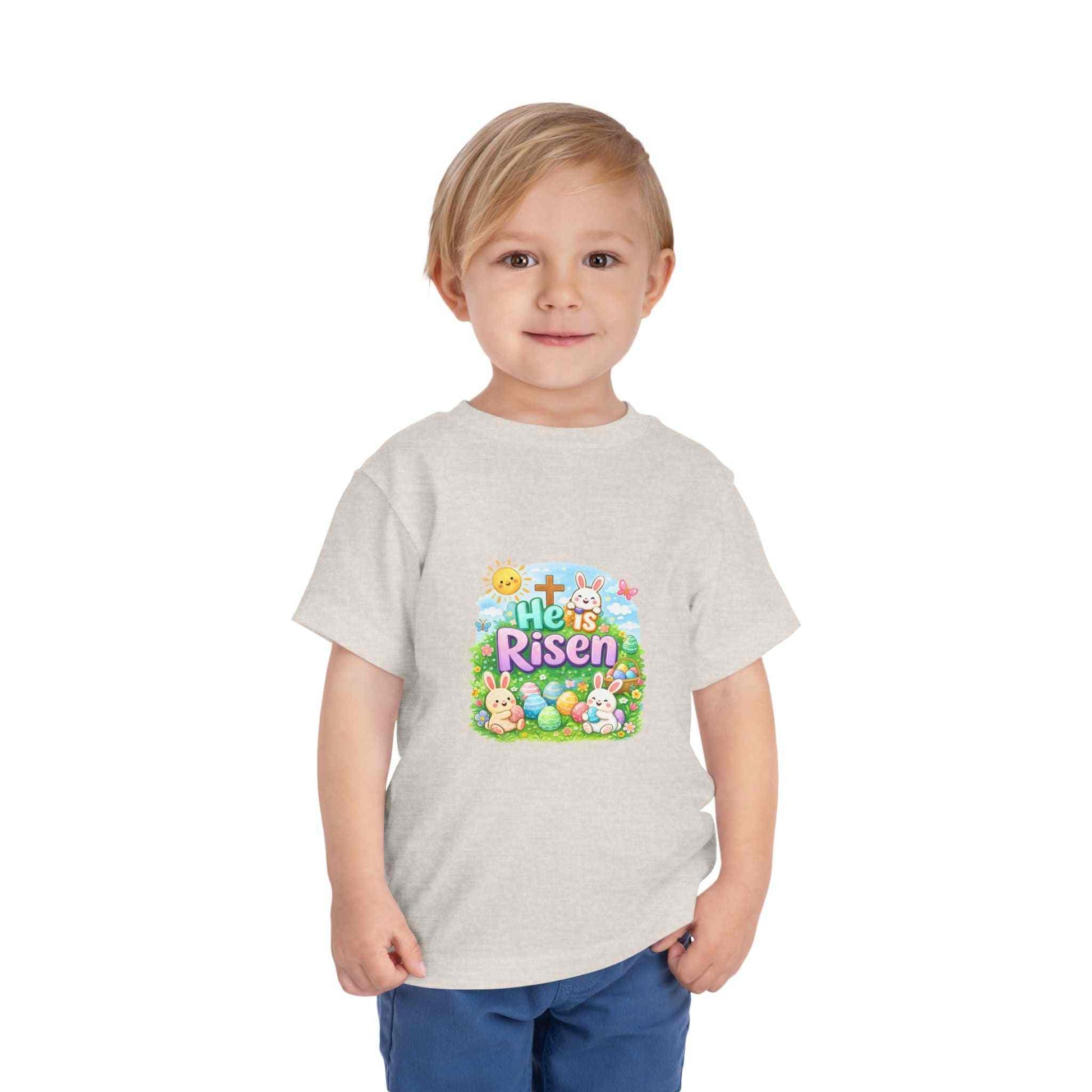 He Is Risen toddler tee with Easter bunny, cross, and pastel eggs design for kids