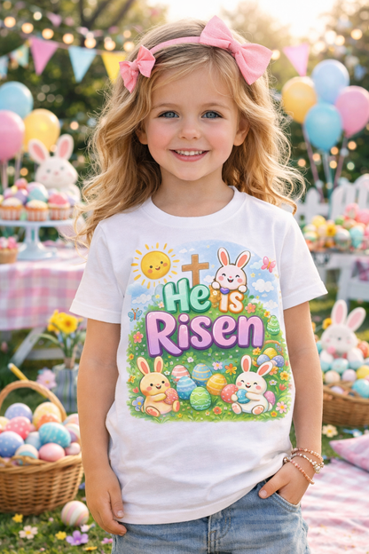 He Is Risen toddler tee featuring Easter bunny, cross, and pastel eggs on soft cotton shirt for kids