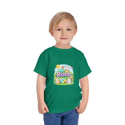 He Is Risen toddler tee with Easter bunny, cross, and pastel eggs design on soft cotton shirt