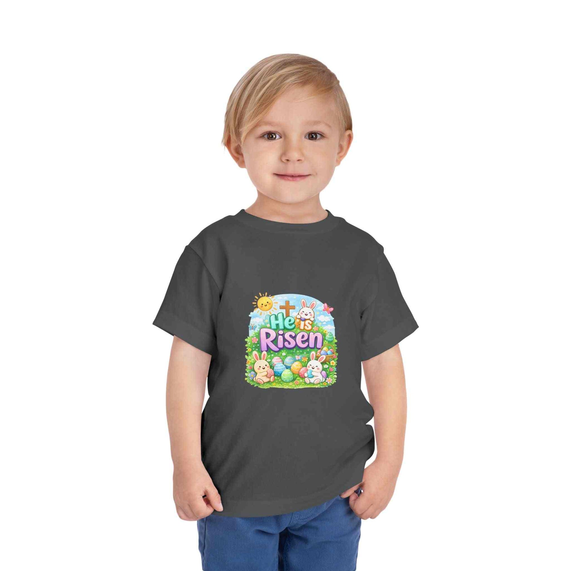 He Is Risen toddler tee with Easter bunny, cross, and pastel eggs design on soft cotton kids shirt